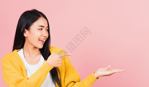 女人微笑着站着伸出手指女孩粉色游客快乐商业学生女性毛衣管理人员化妆品背景图片