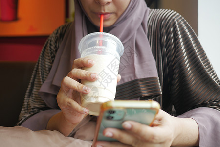 在咖啡馆喝香蕉奶昔的年轻妇女牛奶液体香蕉白色女性眼镜奶制品奶油饮料背景图片
