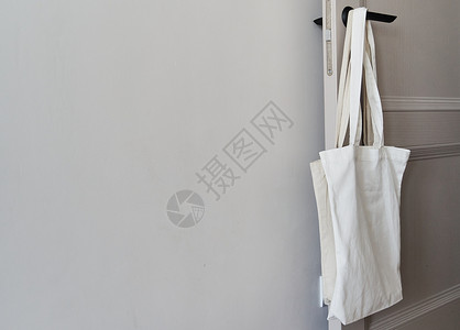 白色生态友好袋挂在门把手上 罐装袋样机棉布小样模板市场手提袋帆布包亚麻购物回收背景