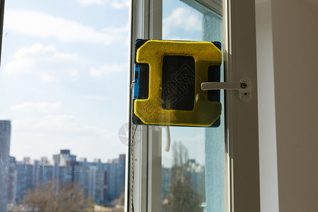 机器人窗户清洁器在脏窗户上工作 用智能设备打扫房子 擦窗自动吸尘机器人 居家好帮手家务安全控制机器帮手力量真空摩天大楼智力帮助背景