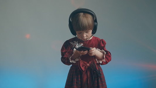 青年才俊穿着大耳机和古代礼服的小女孩 在电话里听音乐工具裙子连衣裙家庭孩子服装才俊宝宝爱好音乐背景