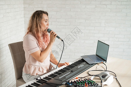 钢琴开课了一位女士在家中使用笔记本电脑录制声乐课程 并在键盘上伴奏 老师对着话筒唱了一首歌 并弹奏了电子钢琴 博主正在录制视频公寓屏幕职业背景