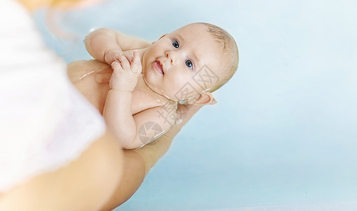 扶着浴缸婴儿在浴室洗完澡的婴儿 有选择地集中注意力孩子母亲乐趣浴缸生活男生新生喜悦家庭童年背景
