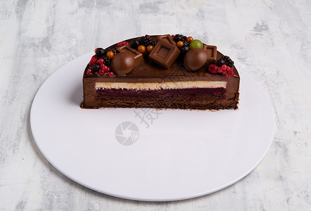 半个巧克力冰淇淋蛋糕的角照 用浆果装饰背景图片