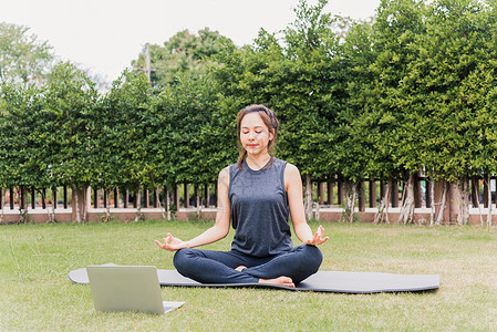 公园电脑妇女在网上视频培训中使用笔记本电脑 在户外练习瑜伽训练女士活动互联网身体姿势女性运动教程冥想背景