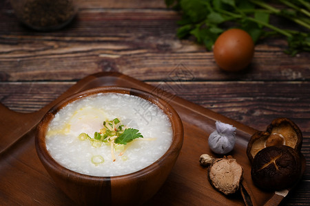 大米粥 有软煮蛋 切姜和木碗中的 冷冻是许多亚洲国家流行的稻米粥种菜 但是背景图片
