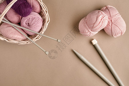 星月粉晶耳线毛线球 柳条盘中的彩色纱线球 用于在米色背景上编织的纱线 针织作为一种针线活 织针和多色纱线看起来很明亮彩线针织袜粉纱篮子黄纱羊背景