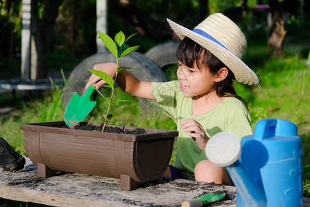 小喷壶戴着帽子的小女孩在花园里帮助她的母亲 一个小园丁 可爱的小女孩在花盆里种花出售 家庭小生意沙拉后院学习孩子女孩蔬菜喷壶环境树苗商背景