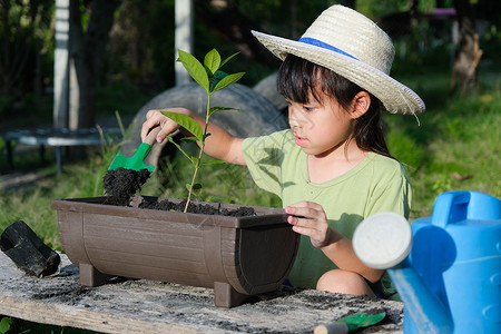 小喷壶戴着帽子的小女孩在花园里帮助她的母亲 一个小园丁 可爱的小女孩在花盆里种花出售 家庭小生意园艺幼苗学习孩子后院环境女儿蔬菜童年商背景