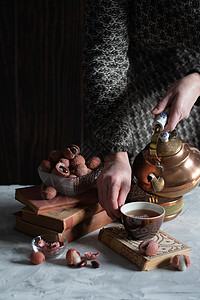 一个女人从铜茶壶里倒茶水 泡到杯子里 喝着莱奇和温柔的生活爱好静物茶会女性喝咖啡注意力文化荔枝桌子古董背景图片