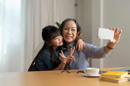 小女孩照片快乐的亚洲微笑老奶奶和小女孩在手机上自拍很开心 快乐的奶奶和小孩玩在手机上拍照背景