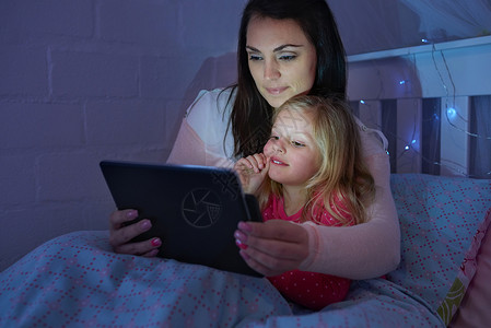 再等五分钟 妈妈 拍摄的是一对母女坐在床上 在数字平板电脑上阅读睡前故事背景图片