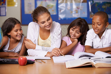 一位年轻的老师坐在她的三个少数民族学生的旁边 通过教科书阅读书本 (笑声) (掌声)背景图片