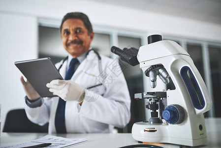 与众不同的医学研究 一张显微镜在实验室桌子上的照片 一位科学家在后台使用数字平板电脑背景图片