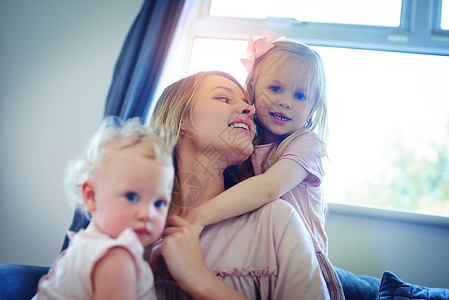 家庭 幸福的源泉 拍摄了两个可爱的姐妹在家里与母亲的亲密关系背景图片