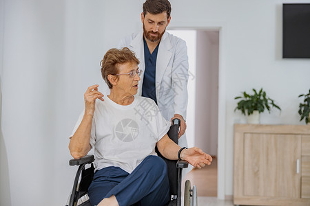 专业医生将坐轮椅的病人带到诊所医院病房治疗 由专业医生接诊男性护士走廊药品房间老年女士保健女性帮助背景