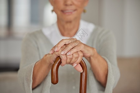 在疗养院里手拿拐杖的老年残疾妇女 老年妇女手持助行器 在医疗机构放松 同时在辅助生活之家使用拐杖支撑的特写镜头背景图片