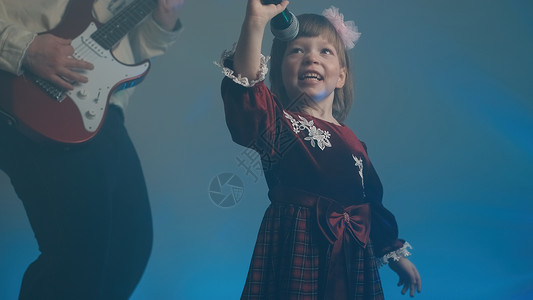 穿旧礼服的小女孩在舞台上唱歌 她父亲弹电吉他油烟机麦克风才俊幼儿园金属复古蓝色孩子们家庭重音乐背景图片