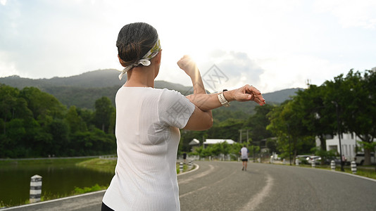 观察中年女士的后视 暖和起来 在上午锻炼前伸展手臂 健康 运动和健康的生活方式概念背景图片