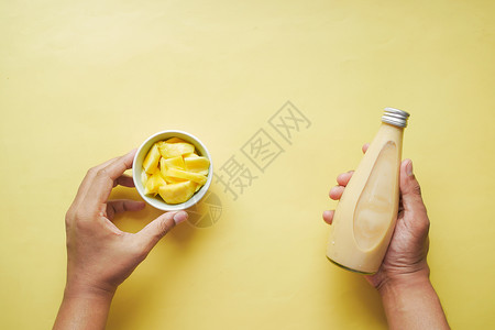 黄底的芒果和新鲜芒果瓶子橙子奶昔排毒玻璃热带牛奶果汁背景图片