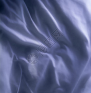 蓝色织物背景的顶视图 起皱的天然亚麻材料 带有柔和褶皱的光滑缎面或天鹅绒床单 豪华灰色布料的特写纹理 抽象深色丝绸图案或折痕背景图片