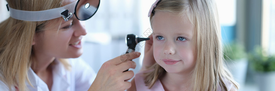 耳炎一名女性在诊所的眼科医生看着一个女孩的耳朵检查疾病耳镜孩子们诊断职业专家女孩药品听力背景