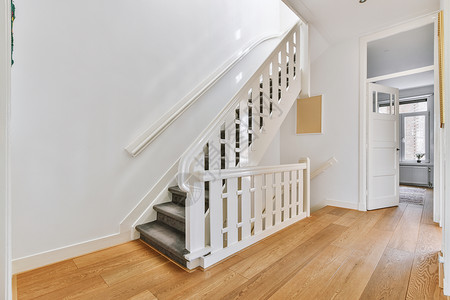 在宽敞的公寓大厅中的木楼梯走廊木头大堂绘画奢华白色住宅房子风格地面背景