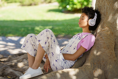 黑人女人在树旁听音乐高清图片