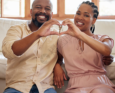 做新房子素材年轻的非洲裔美国夫妇微笑着做一个心形手势 他们的手拿着一把钥匙 一起坐在他们新房子的地板上 丈夫和妻子很高兴搬进自己的家背景