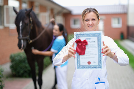 女兽医持有马匹背景的医学证明书 并拥有背景图片