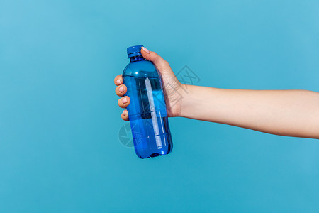 电解质水人手将瓶水放在蓝色背景上矿物饮料女士广告生活电解质波纹饮用水茶点液体背景