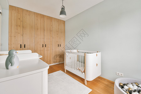 带婴儿床边框带小床的轻便舒适婴儿房婴儿财产白色住宅婴儿床风格房子木地板家具窗户背景