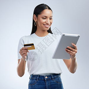 让您的财富增长的方法不止一种 一位女士拿着银行卡 在灰色背景下使用数字平板电脑背景图片
