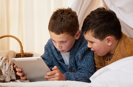 点燃他们好奇的心 两兄弟在家里的毛毯堡垒下一起使用数字平板电脑背景图片
