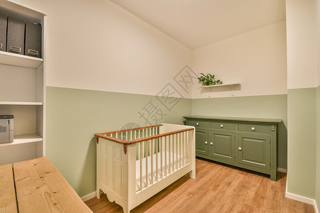 带婴儿床边框带小床的轻便舒适婴儿房公寓白色窗户婴儿床木地板扶手椅风格婴儿家具房子背景