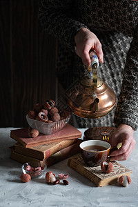 一个女人从铜茶壶里倒茶水 泡到杯子里 喝着莱奇和温柔的生活闲暇成人静物注意力桌子仪式文化时间阅读茶会背景图片