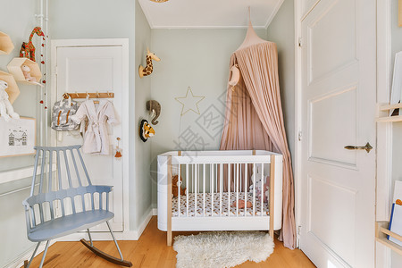 带婴儿床边框带小床的轻便舒适婴儿房窗户木地板婴儿财产椅子家具白色住宅公寓装饰背景