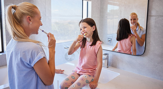 早上 可爱的小女孩准备和妈妈一起刷牙 可爱的小女儿仰望妈妈 树立了口腔卫生和照顾牙齿的好榜样背景图片