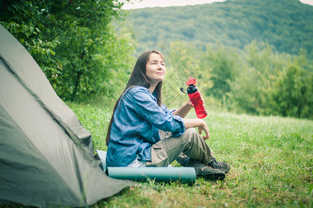 妇女在帐篷附近的山上 是可喜的女士森林活动远足旅游女性岩石享受游客成人背景