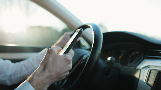 坐在车里用手机打在线信息的面目全非的人的特写手 在汽车中使用电话的商务人士特写视图 事故保险 聊天司机背景