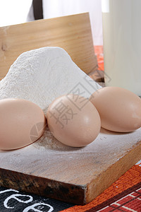 3个鸡蛋加面粉的切开板上的三只鸡蛋白色木头食物桌布背景图片