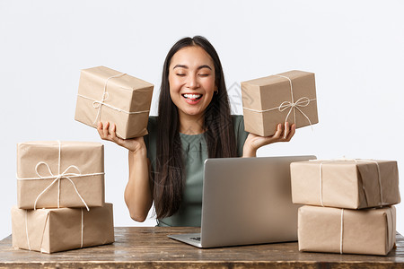 小企业主 创业和电子商务概念 面带微笑的成功店长 拥有互联网商店包装客户订单的女商务人士 用于运输 拿着盒子和使用笔记本电脑背景图片