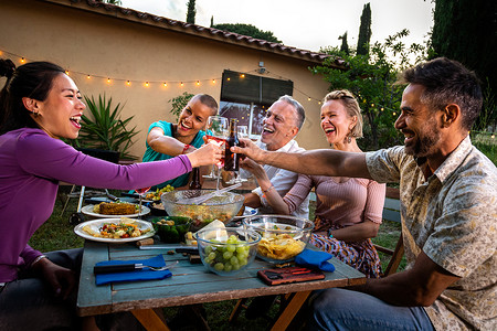 亚洲女人在日落的烧烤花园晚宴上 喝着葡萄酒 笑和玩乐 来庆祝祝酒背景图片