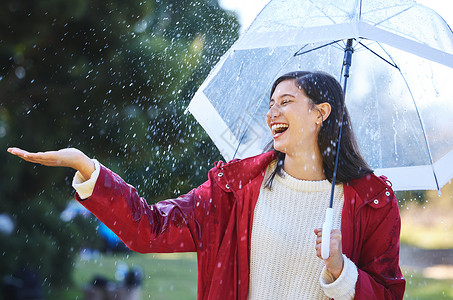 女人的伞我喜欢我皮肤上下雨的感觉 一个年轻女人拿着雨伞站在雨中 带着雨伞背景