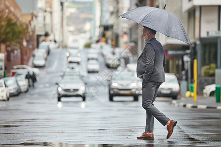 男人想挣钱这样的天气让我想躺在床上 下雨天走路上班的英俊商务人士背景