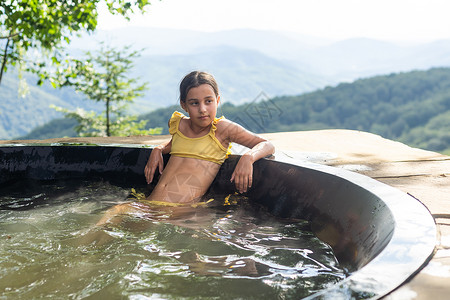 空气能热水夏天 在山里的热水浴缸里的小姑娘女性成人森林卫生保健温泉增值税照片空气洗澡背景