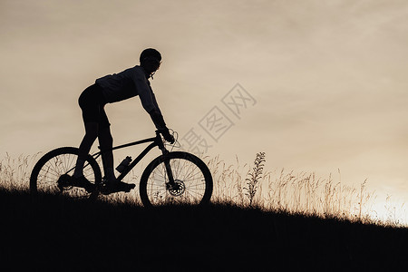 职业赛车运动员骑着下山在日落的自行车上骑着脚踏板滑雪运动者运输高清图片素材