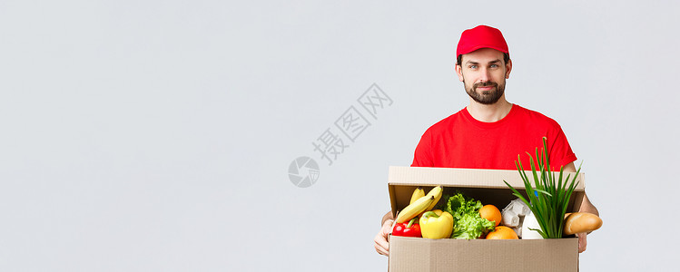 杂货和包裹递送 covid19 检疫和购物概念 身穿红色制服帽和 T 恤的帅气快递员 带杂货包裹 送货到客户家 快速运送餐厅蔬菜背景
