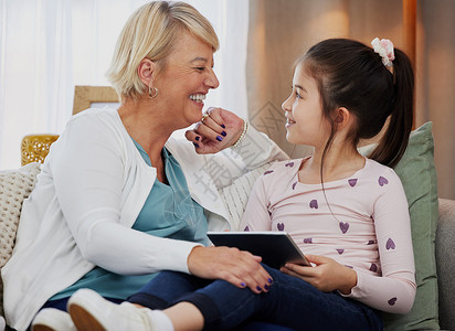 那个很有教育意义 对吧 一个可爱的小女孩和她的祖母坐在家里使用数字平板电脑背景图片