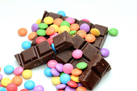 巧克力装满糖果 有各种明亮的颜色和巧克力棒碎片小吃圆形团体食物橙子蓝色黄色红色绿色背景图片